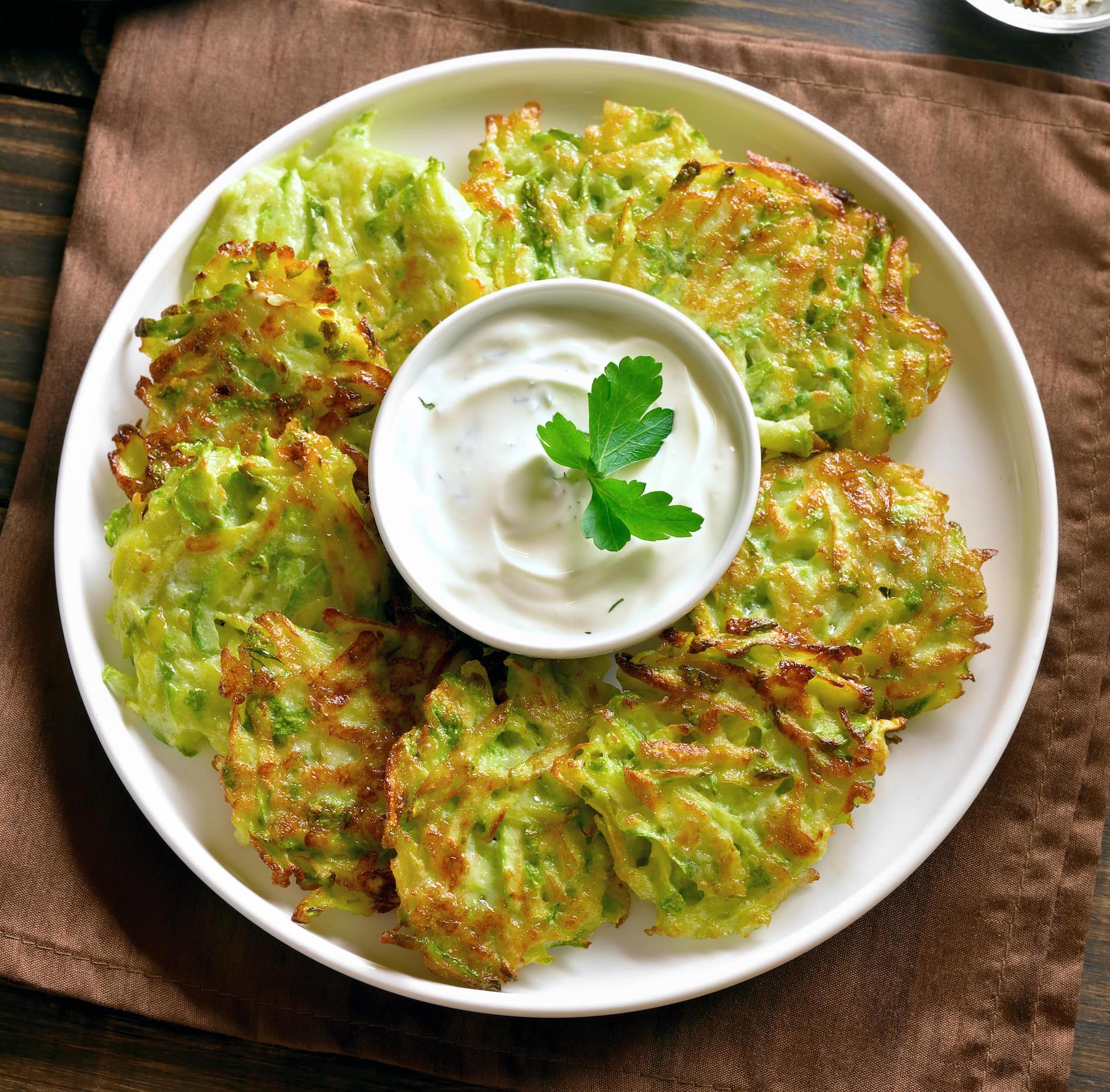 frittelle di zucchine in un piatto con una salsa al centro. Antipasto per iniziare il menù per l'8 dicembre