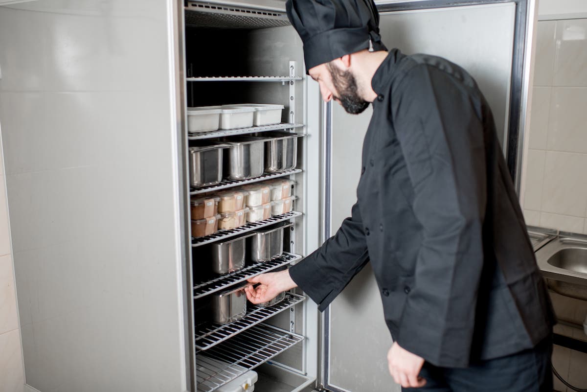 chef guarda nel frigo del ristorante e controlla al temperatura